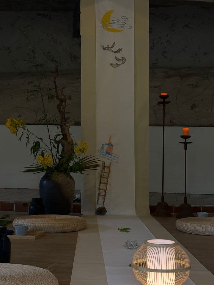 禅修空间内展示黄花插花、纸质月亮和羽毛装饰、竹编灯笼和黑色烛台