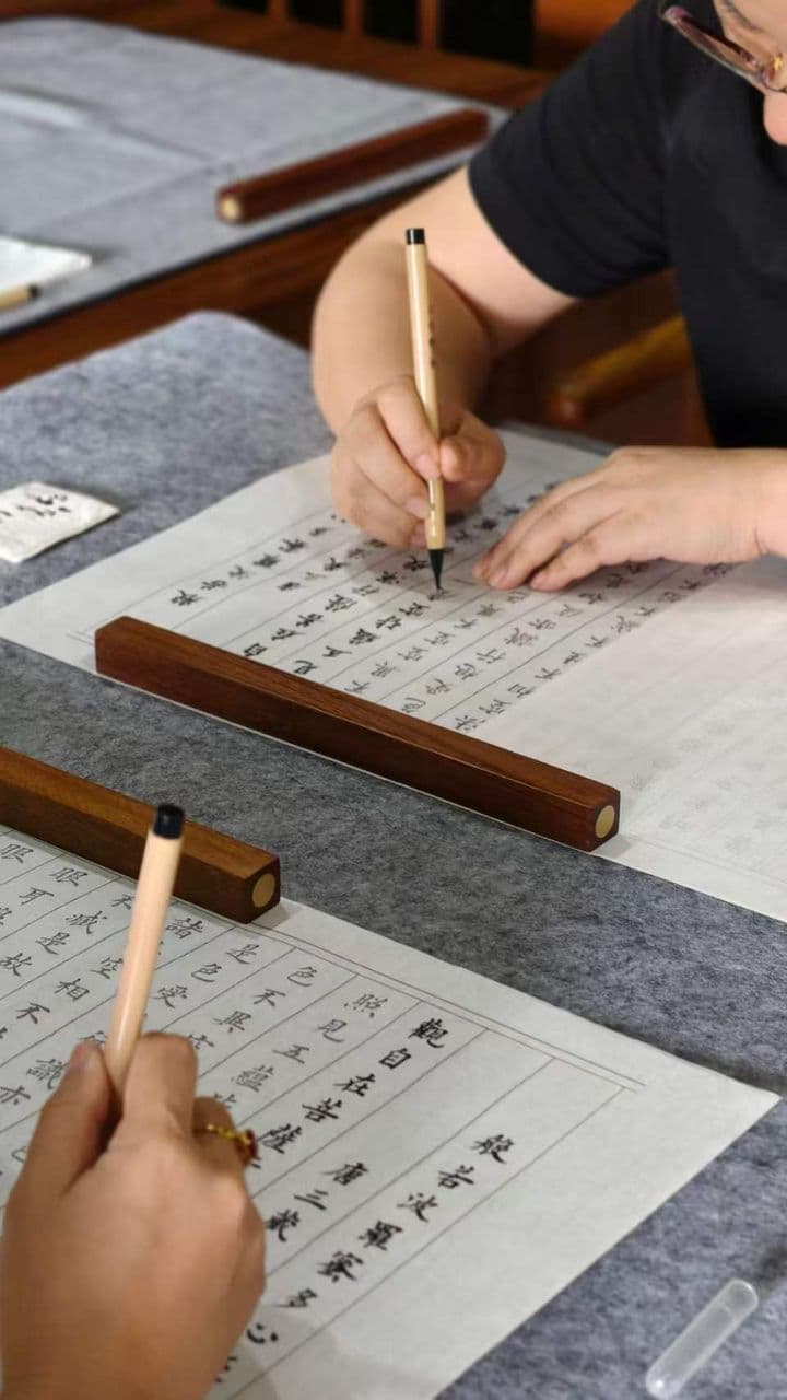 两人在木制笔架上用毛笔练习书写汉字